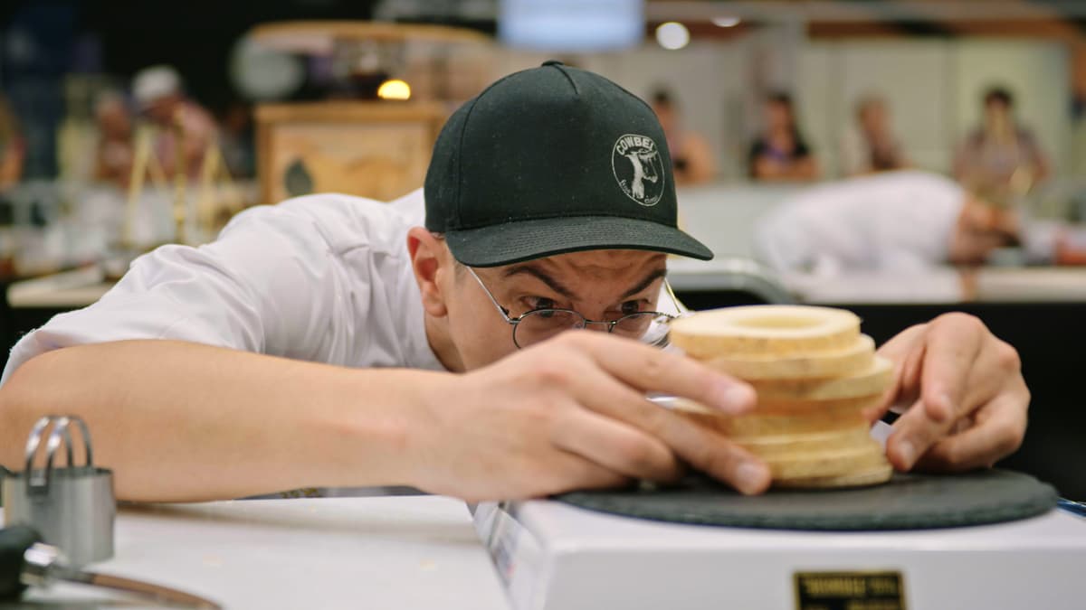 Cheesemonger examining a wheel of cheese